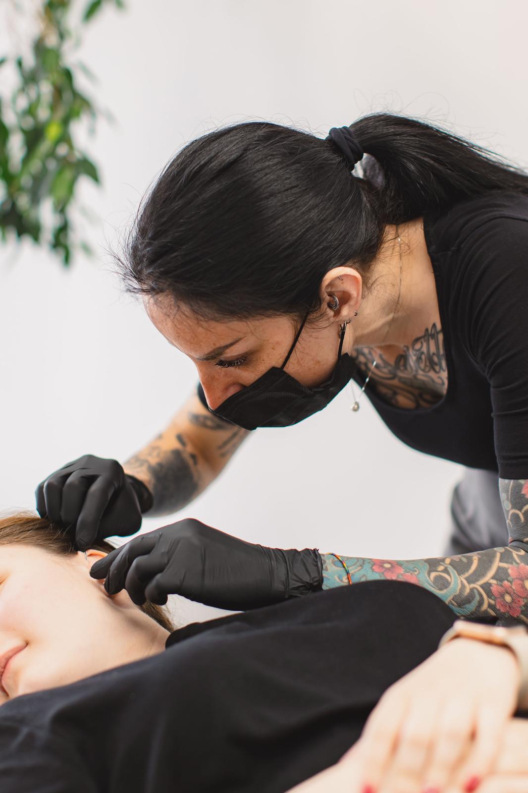 Alessandra concentrata durante un piercing all'orecchio